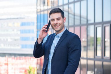 Şehirde cep telefonuyla konuşan gülümseyen iş adamının yan portresi