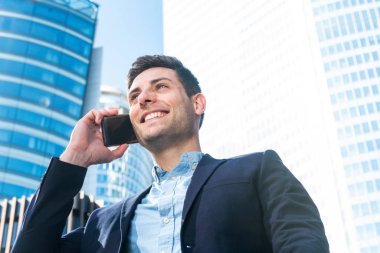 Şehirde cep telefonuyla konuşan gülümseyen iş adamının portresini kapat.