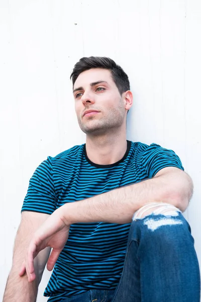 Portrait Handsome Young Man Sitting White Wall Looking Away — Stock Photo, Image