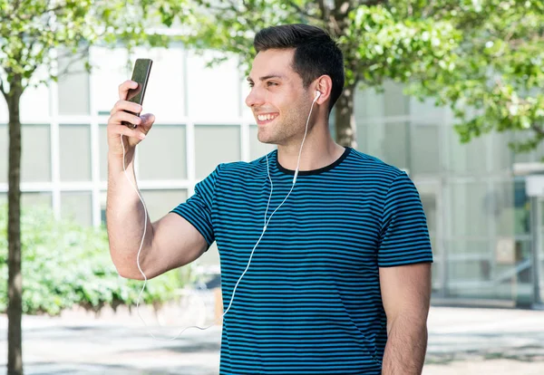笑顔若い男の携帯電話を外に持っていると自画撮りのサイドポートレート — ストック写真