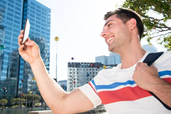 Boczny Portret Szczęśliwego Młodego Człowieka Torbą Robienie Selfie Telefonem Mieście — Zdjęcie stockowe