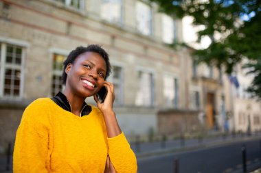 Close up portrait smiling young black woman talking with cellphone in city