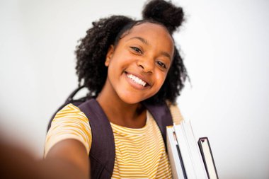 Afro-Amerikan kız öğrencinin, izole edilmiş beyaz arka planda selfie çektiği portreyi kapatın.