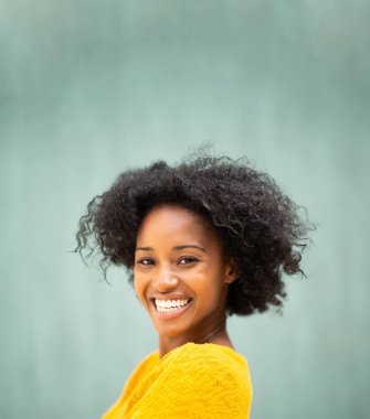 Yakından bakınca gülümseyen siyah bir kadın yeşil arka plandan başka tarafa bakıyor.