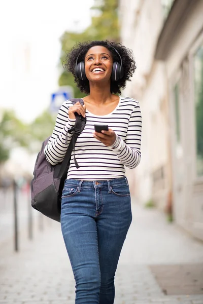Portret Uśmiechnięta Młoda Afroamerykanka Chodząca Torbą Telefonem Komórkowym Słuchająca Muzyki — Zdjęcie stockowe