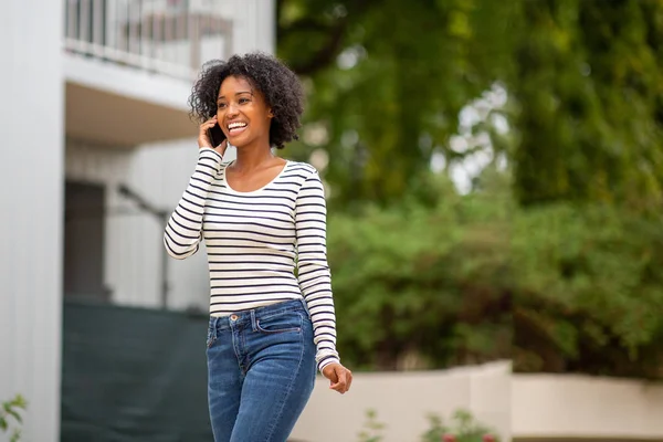 Retrato Sonriente Mujer Afroamericana Caminando Hablando Con Teléfono Celular Afuera —  Fotos de Stock