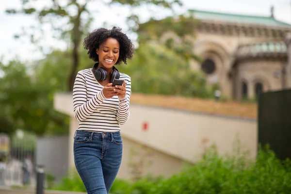 Retrato Sonriente Joven Mujer Negra Caminando Con Teléfono Celular Auriculares —  Fotos de Stock