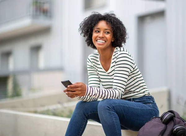 Portret Lachende Jonge Zwarte Vrouw Zitten Buiten Met Mobiele Telefoon — Stockfoto