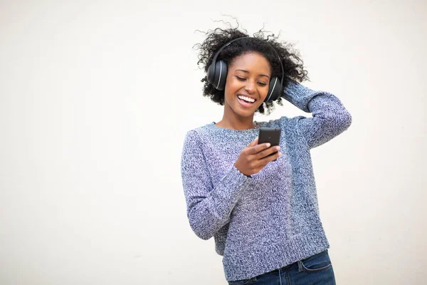 肖像画幸せな若いアフリカ系アメリカ人の女性は 孤立した白い背景によって電話やヘッドフォンで音楽を聴く — ストック写真