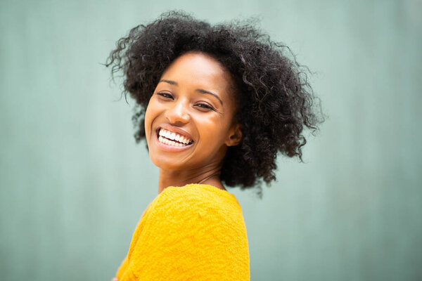 Close up side portrait smiling beautiful young black woman looking away by green background