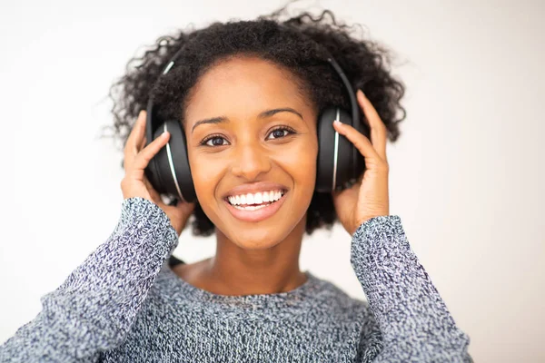 Afro-Amerikan gülümseyen kadın kulaklıkla müzik dinliyor.