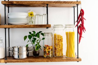 Tabaklar ve cam kavanozlar, mısır gevreği ve raflarda makarna.