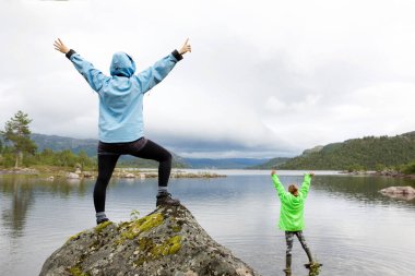 Göl kenarında kolları havada iki genç kadının portresi.