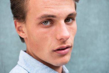 Yüzünde ciddi bir ifade olan yakışıklı bir genç adam.