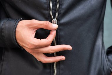 Erkek eli, deri ceketin fermuarını çekiyor.