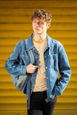 Sarı arka planda çantalı havalı genç adam portresi. 