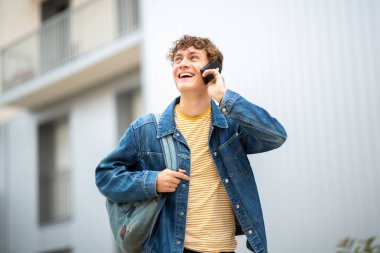 Portre genç adam cep telefonuyla konuşuyor ve gülümsüyor.