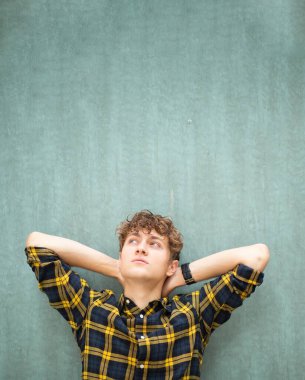 Düşünen adamın portresi yeşil duvara yaslanmış, elleri başının arkasında.