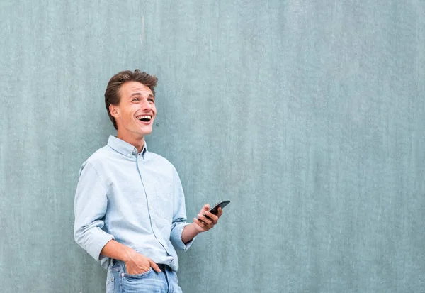 Zijportret Lachende Jonge Man Met Mobiele Telefoon Omhoog Kijkend — Stockfoto