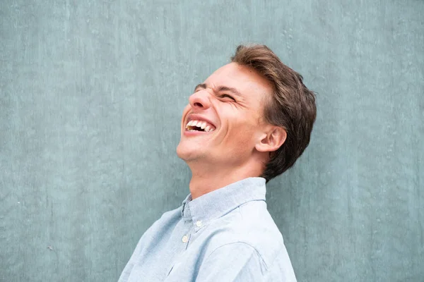 Close Boczny Portret Młody Człowiek Śmieje Się Przez Zieloną Ścianę — Zdjęcie stockowe