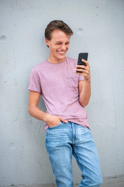 肖像幸せな若いです男もたれ壁に対して見ます携帯電話 — ストック写真