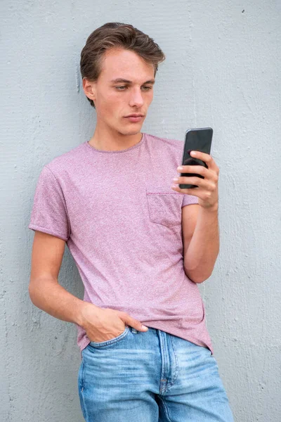 Portret Ernstige Jongeman Leunend Tegen Muur Kijken Naar Mobiele Telefoon — Stockfoto