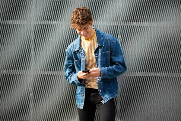 Portrait Jeune Homme Souriant Regardant Téléphone Mobile Par Mur Gris — Photo