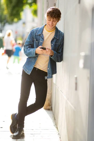 Retrato Sonriente Joven Mirando Teléfono Móvil Mientras Apoya Contra Pared —  Fotos de Stock