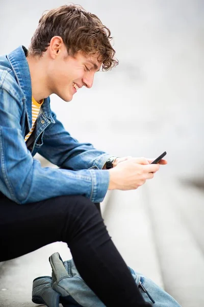 Портрет Счастливого Молодого Человека Сидящего Снаружи Смотрящего Сотовый Телефон — стоковое фото