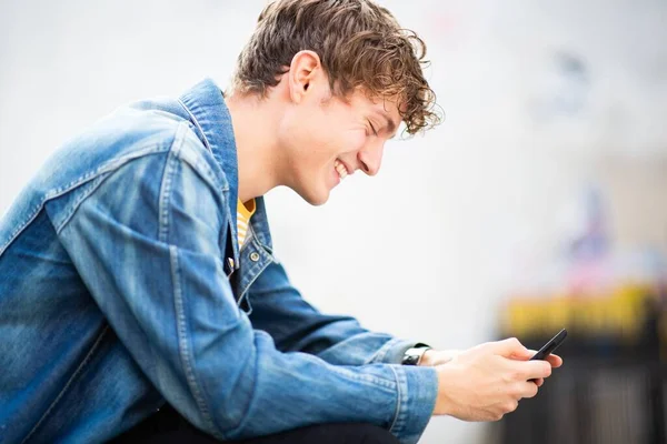 Zavřít Boční Portrét Šťastný Mladý Muž Sedí Venku Dívá Cellphon — Stock fotografie