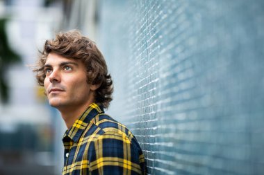 Kapalı portre yakışıklı genç adam duvara yaslanmış yukarı bakarak düşünüyor