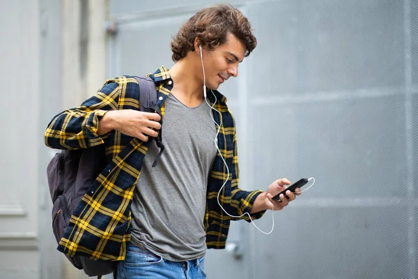 サイドポートレート若い男歩くとともに携帯電話やイヤフォン外 — ストック写真