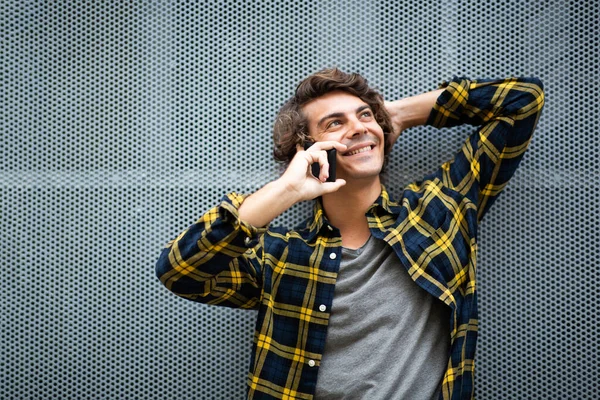 Duvara Yaslanmış Cep Telefonuyla Konuşan Gülümseyen Genç Adam Portresi — Stok fotoğraf