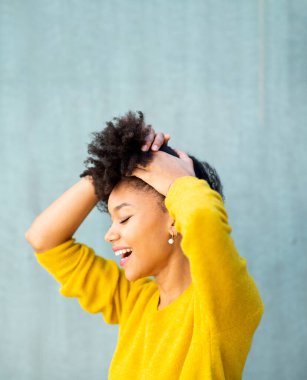 Yakın plan portresi, gülümseyen siyah bir kadın, yeşil arka planda, afro saçlı.