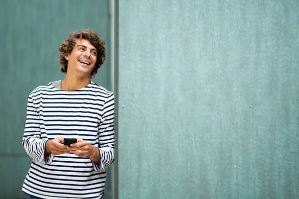 Portret Koele Jongeman Lachen Met Mobiele Telefoon Door Groene Achtergrond — Stockfoto