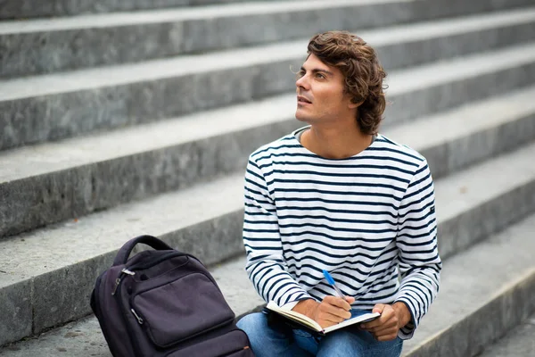 Retrato Estudante Universitário Masculino Sentado Lado Fora Escrevendo Livro Pensando — Fotografia de Stock