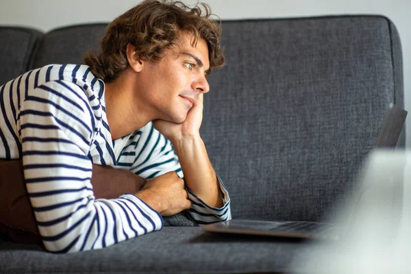 Retrato Joven Acostado Sofá Casa Mirando Pantalla Del Ordenador Portátil —  Fotos de Stock