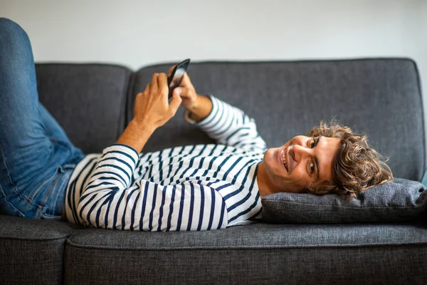 Portret Gelukkige Jongeman Ontspannen Bank Met Mobiele Telefoon — Stockfoto