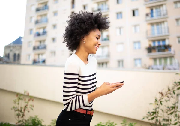 Retrato Lateral Sonriente Joven Mujer Negra Caminando Con Teléfono Móvil — Foto de Stock