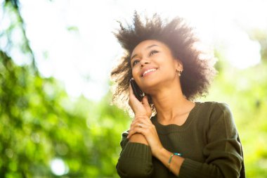 Güneşli bir günde güzel, Afro-Amerikan bir kadının cep telefonuyla konuştuğu portreyi kapat.