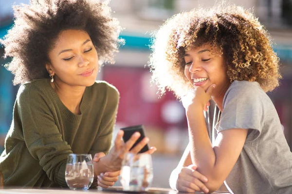 Portré Két Boldog Fiatal Fekete Nők Szabadtéri Kávézóban Nézi Mobiltelefon — Stock Fotó