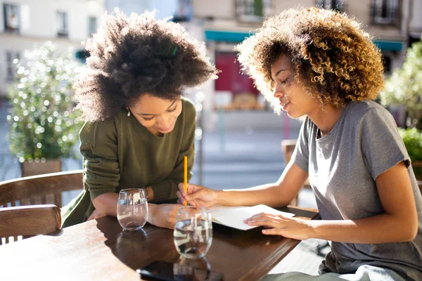 两个年轻的非洲裔美国妇女坐在户外咖啡馆里的画像 — 图库照片