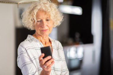 Cep telefonu ekranına bakan yaşlı kadının portresini kapat 