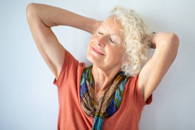 Beyaz arka planda elleri ve gözleri kapalı gülümseyen yaşlı kadın portresini kapat.