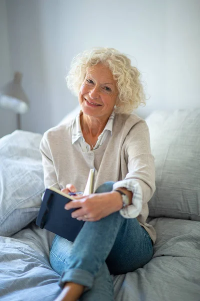 Porträt Lächelnde Ältere Frau Sitzt Auf Bett Und Schreibt Tagebuch — Stockfoto