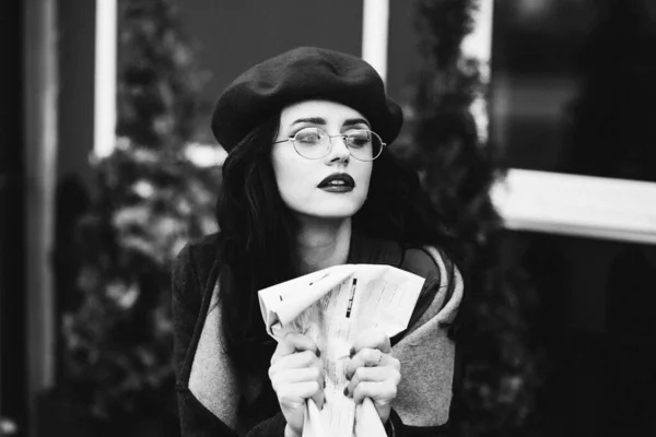 girl beret glasses, in a coat is sitting in a cafe