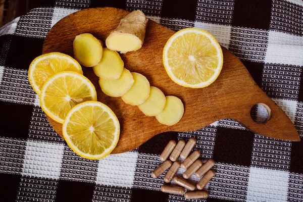 limon ve zencefil tahta bir tahtanın üzerinde yatar. Vitamin Tabletleri.