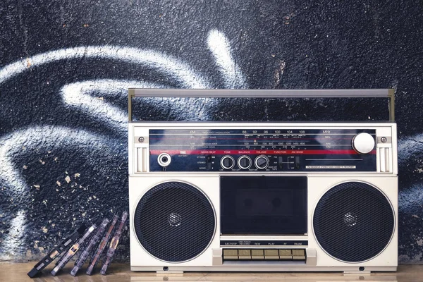 Yerde ve graffiti arka planında kasetler olan klasik müzik kutusu. Geçmişin müziğinin anısı.