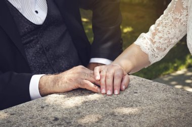 Zarif gelin ve damadın taşın üstünde alyansları olan elleriyle dokunuşlarının yüzsüz fotoğrafı.