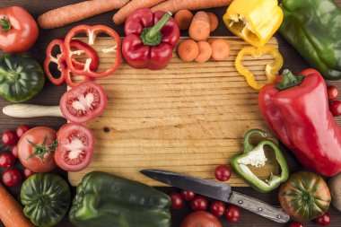 Etrafı taze ve sağlıklı çiğ sebzeler ve eski bir bıçakla çevrili bir tahta kesme tahtasının üst görüntüsü. Mesaj için yer var. Uzayı kopyala Sağlıklı yiyecekler. Doğal ürünler. Doğa ve refah..